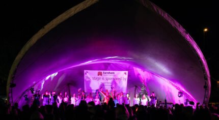 Crowd of people looking at stage lit up with purple lights