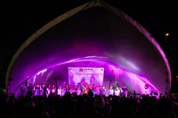 Crowd of people looking at stage lit up with purple lights