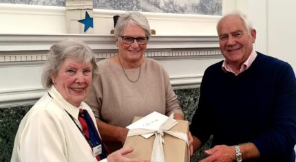 Female presents a gift to a couple.