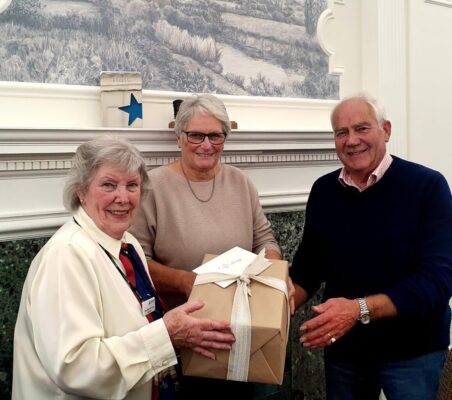 Female presents a gift to a couple.