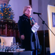 Female on stage speaking into a microphone