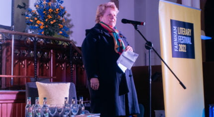 Female on stage speaking into a microphone