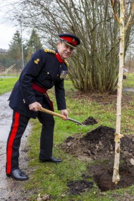 Uniformed male digging a hole