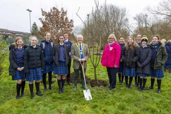 Group of school children, the Mayor and female in pink jacket at a tree planting.