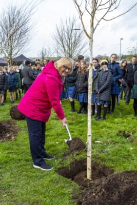Female backfilling a hole after planting a tree.