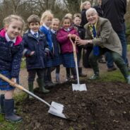 Small group of schoolchildren planting a tree with the Mayor