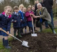 Small group of schoolchildren planting a tree with the Mayor