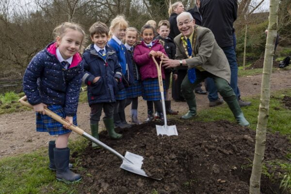 Small group of schoolchildren planting a tree with the Mayor