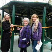 Four people with one cutting a ribbon across entrance to shelter