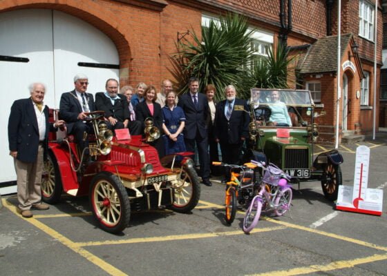 Group of people with two vintage cars and two children's bicycles