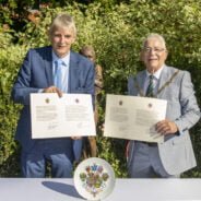 Two men each holding a document.