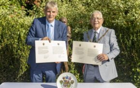 Two men each holding a document.