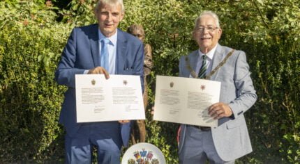 Two men each holding a document.