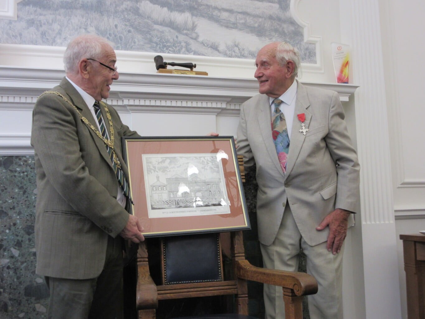 Two males holding a framed sketch. 