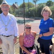 Three people in front of a tennis court.