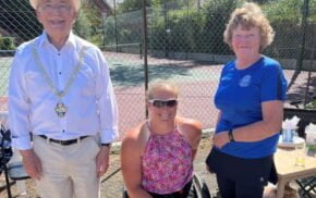 Three people in front of a tennis court.