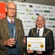 A male holding a glass vase standing next to the Mayor who is holding a certificate