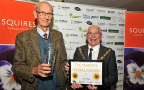 A male holding a glass vase standing next to the Mayor who is holding a certificate