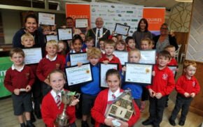 Group of school children holding certificates and trophies