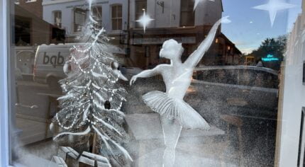 Snowy scene of a Christmas tree and ballerina on a shop window