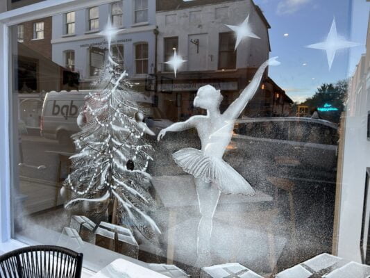 Snowy scene of a Christmas tree and ballerina on a shop window