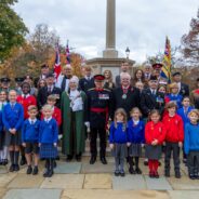 Group of school children and adults at war memorial