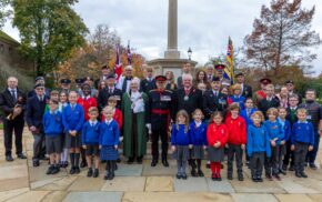 Group of school children and adults at war memorial