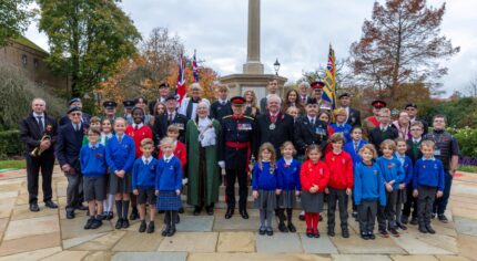 Group of school children and adults at war memorial