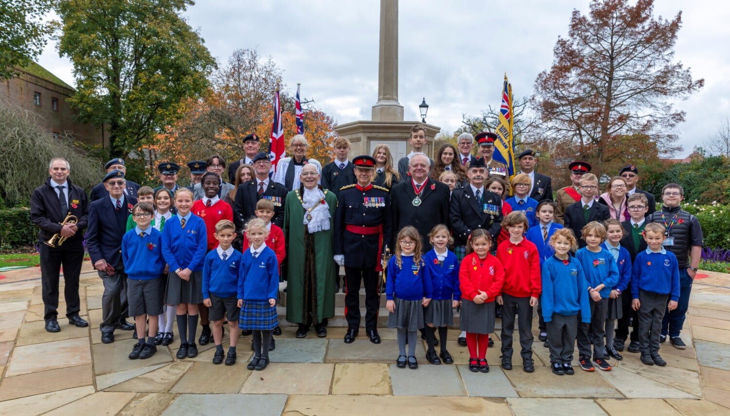 Group of school children and adults at war memorial