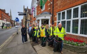 Group of people in high visibility waistcoats holding sacks and litter picks