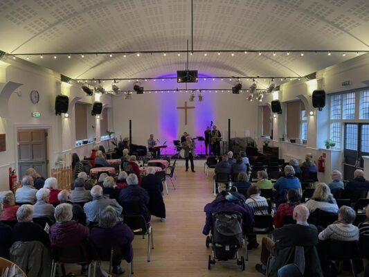 Inside the vineyard church looking down towards stage. Mayor of Farnham doing opening speech with crowd watching.