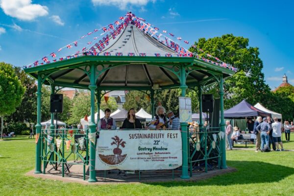 Picture of a bandstand with people under it singing and playing instruments.