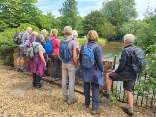 Group of walkers standing at the side of a river.