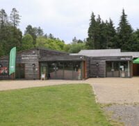 A photo of a wooden activity centre at Alice Holt surrounded by trees and green space.