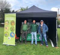 Three males standing inside a small marquee.