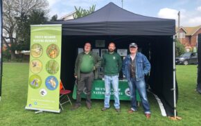 Three males standing inside a small marquee.