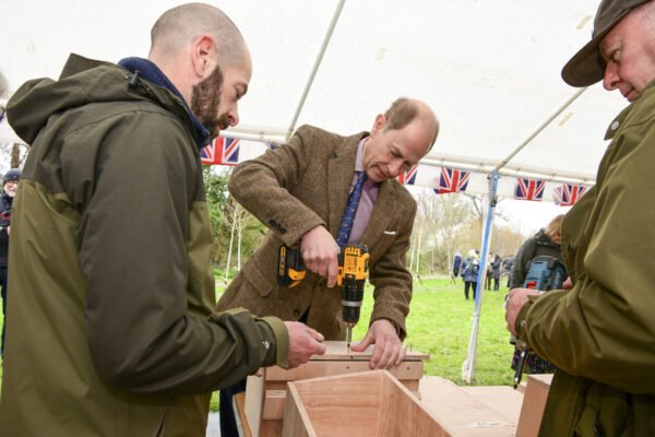 HRH The Duke of Edinburgh drilling a hole in a bird box.