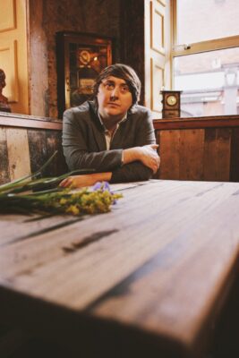 A photo of musician John Blek siting at a table in a public house