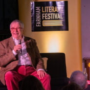 Male sitting on a sofa speaking into a microphone