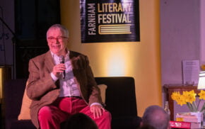 Male sitting on a sofa speaking into a microphone