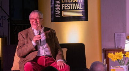 Male sitting on a sofa speaking into a microphone