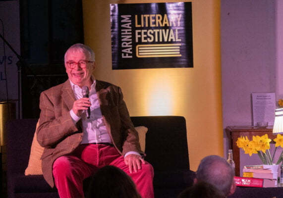 Male sitting on a sofa speaking into a microphone