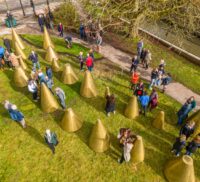 Aerial view of people milling amongst an art installation made up of a series of cones.