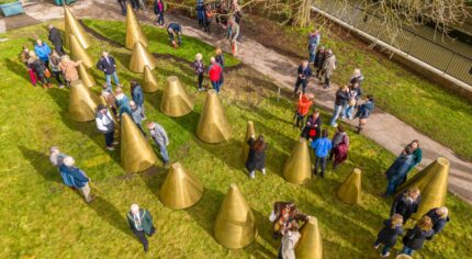 Aerial view of people milling amongst an art installation made up of a series of cones.