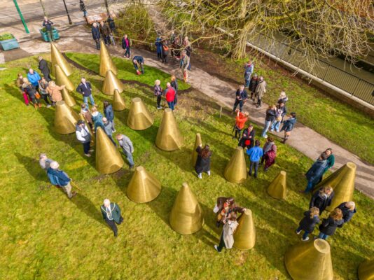 Aerial view of people milling amongst an art installation made up of a series of cones.