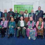 Two rows of people wearing medals on green ribbons.