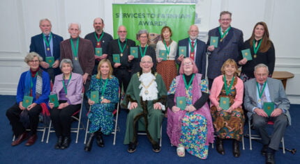 Two rows of people wearing medals on green ribbons.