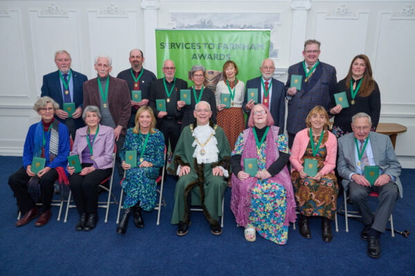 Two rows of people wearing medals on green ribbons.