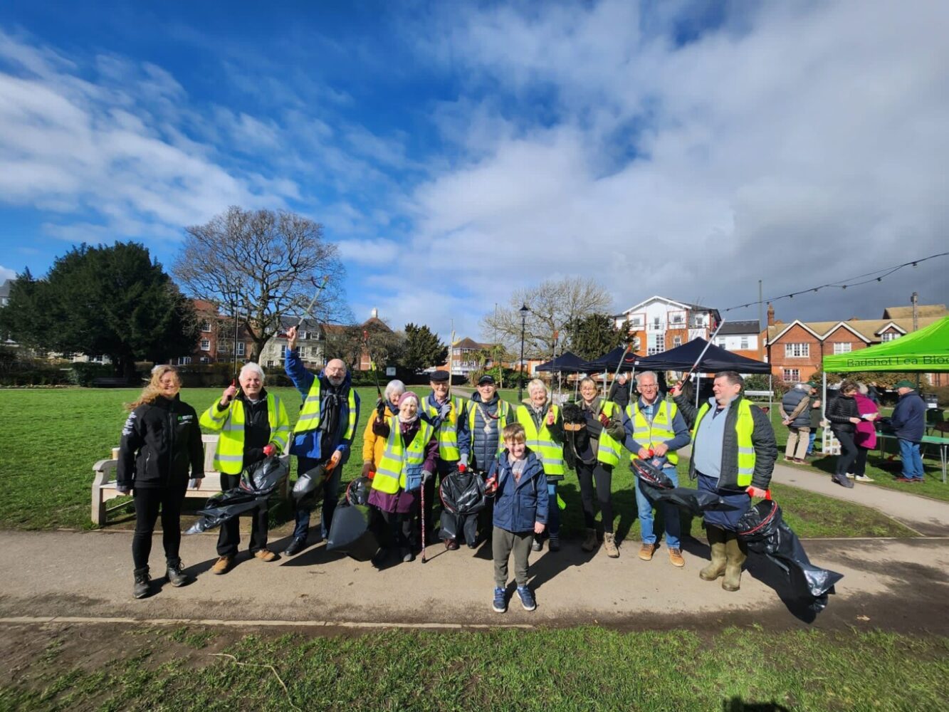 Group of people in high visibility vests holding litter pickers