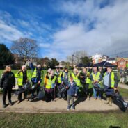 Group of people in high visibility vests holding litter pickers